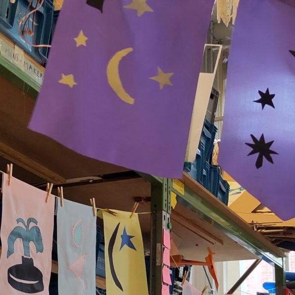 A row of colourful flags signals the installation from far and welcomes future visitors: they were designed and made by the young makers, but also wider community members, invited to contribute during a family workshop.